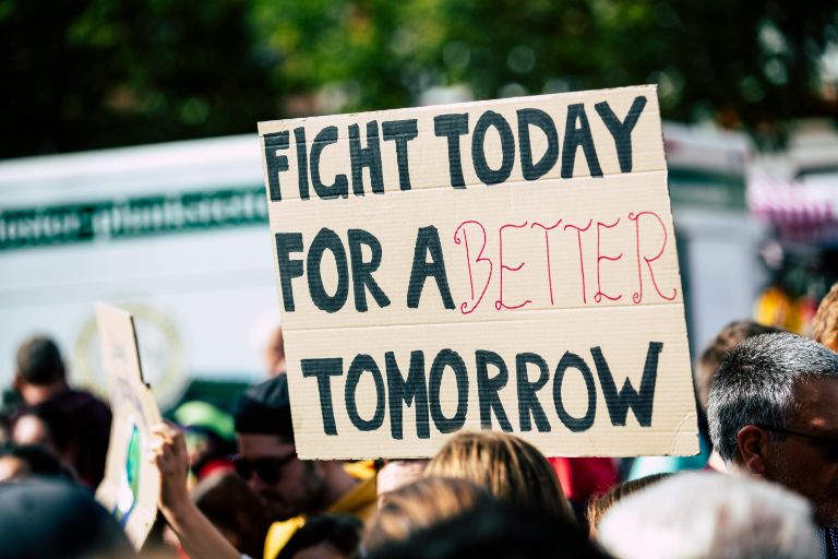 A man holding a board on which the words are FIGHT TODAY FOR A BETTER TOMORROW.