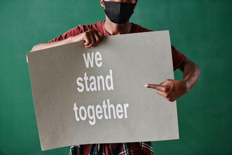 A man is having a board in his hand along the text of We Stand together