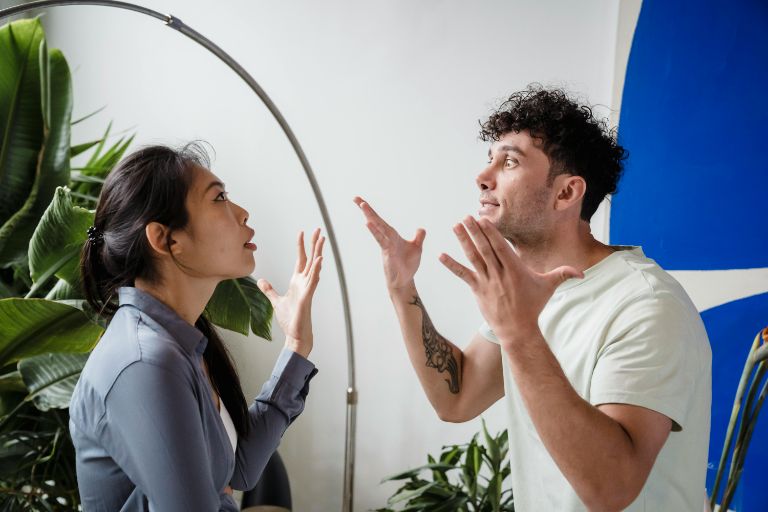 In an office, a man and woman are arguing, showcasing their disagreement through body language and facial expressions.