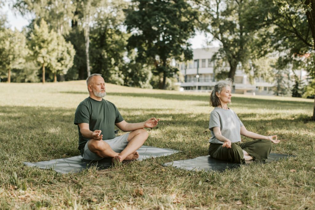 An old man and woman are performing Mindfulness Meditation with yoga practice in the park. 