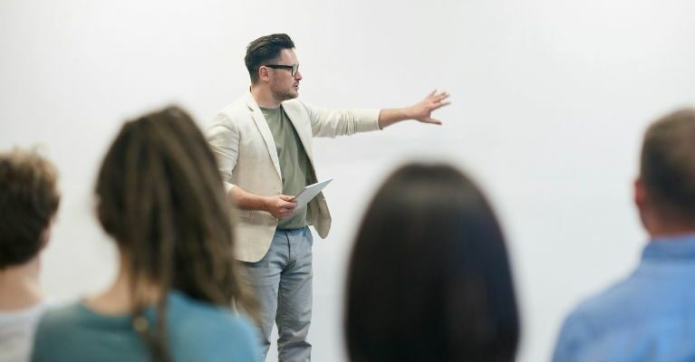 A speaker delivers a presentation to an attentive group of individuals in a professional setting.